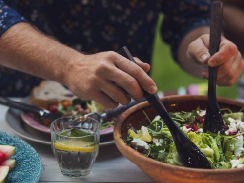 Midsection of man mixing salad at table during garden party